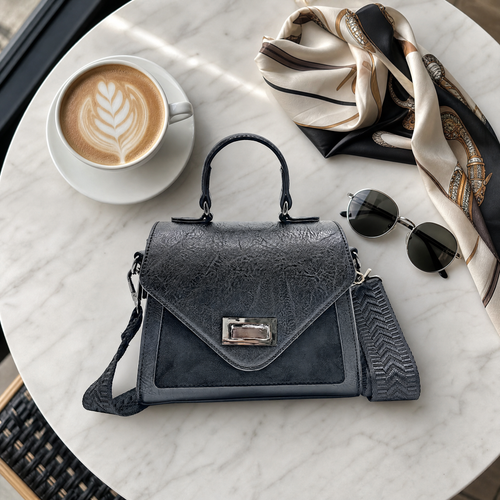 D.Y. Valle Aurora Mini Satchel Bag in slate grey flat-laid on a marble café table with a latte, silk scarf and round sunglasses.